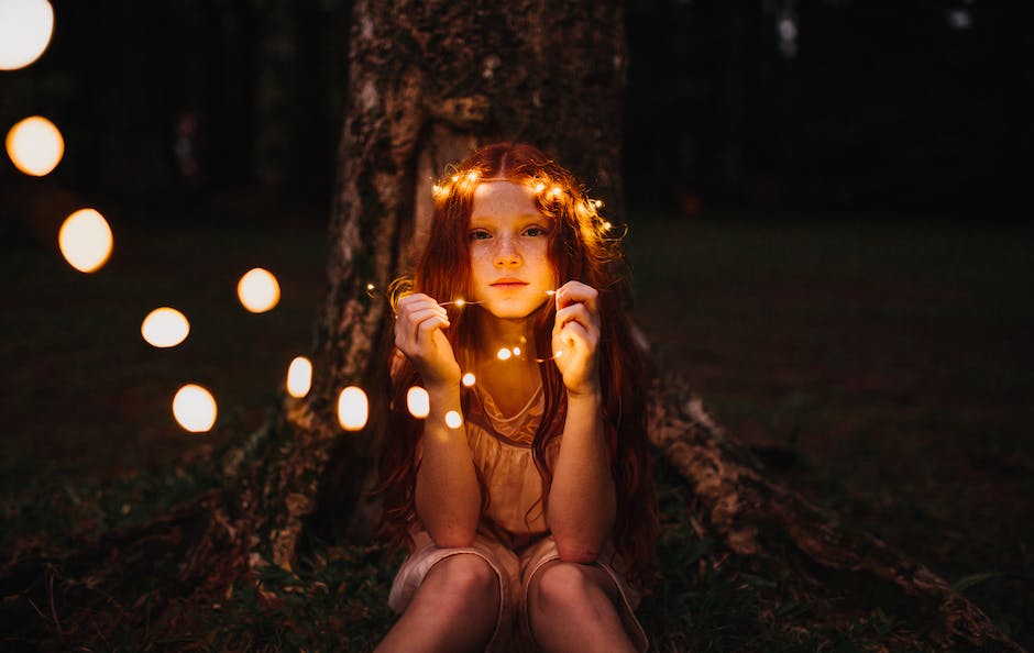 Image of a person selecting a tree for fairy lights by holding a string of lights over different trees, trying to find the right one.
