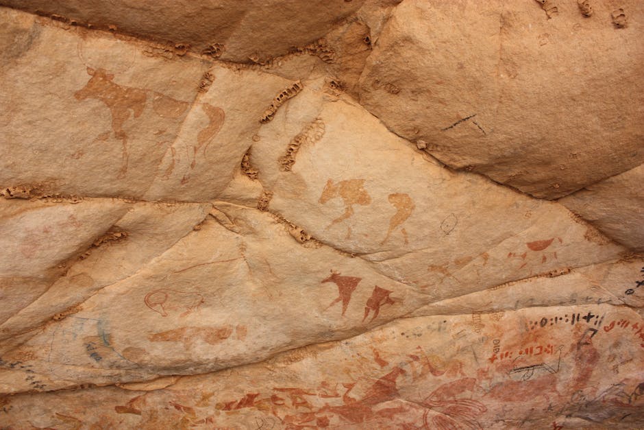 A cave with prehistoric wall art, showing various animals and human figures.